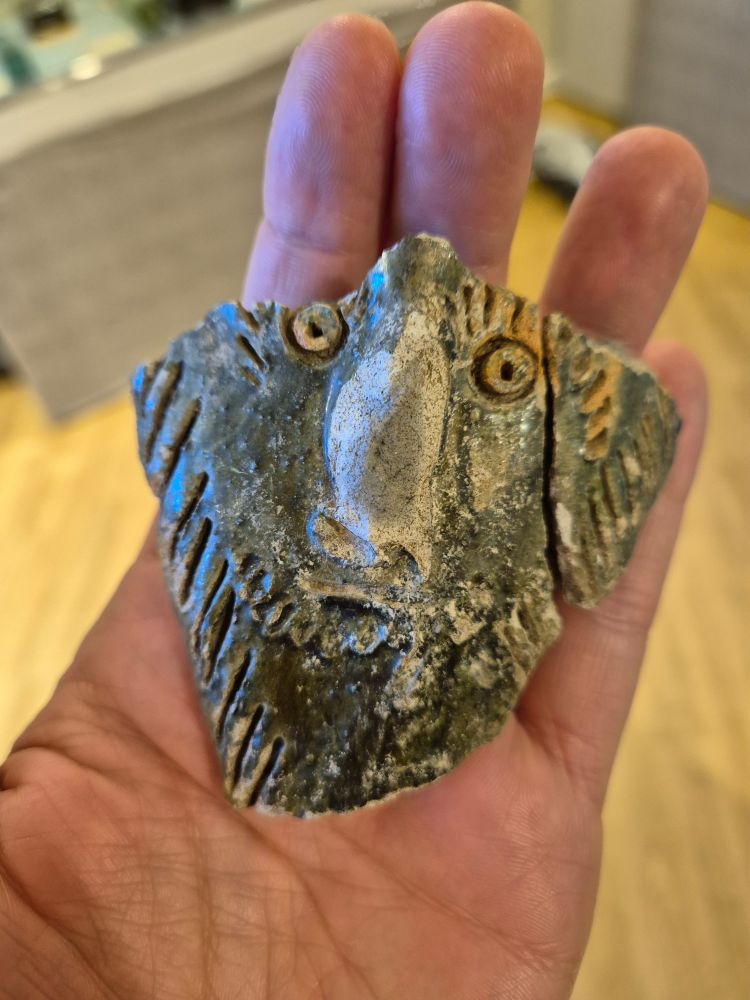 Ceramic face on a shard of 14th century pottery.