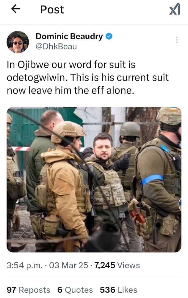 X post from Dominic Beaudry explaining the word for suit in Ojibwe is odetogwiwin, and since President Zelensky is in his current 'suit', he should be left the eff alone. Picture shows President Zelensky in protective vest looking towards camera and standing among several helmeted soldiers