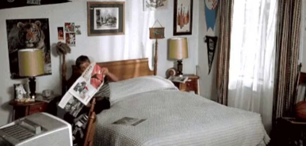 a young boy is sitting on a bed reading a magazine .