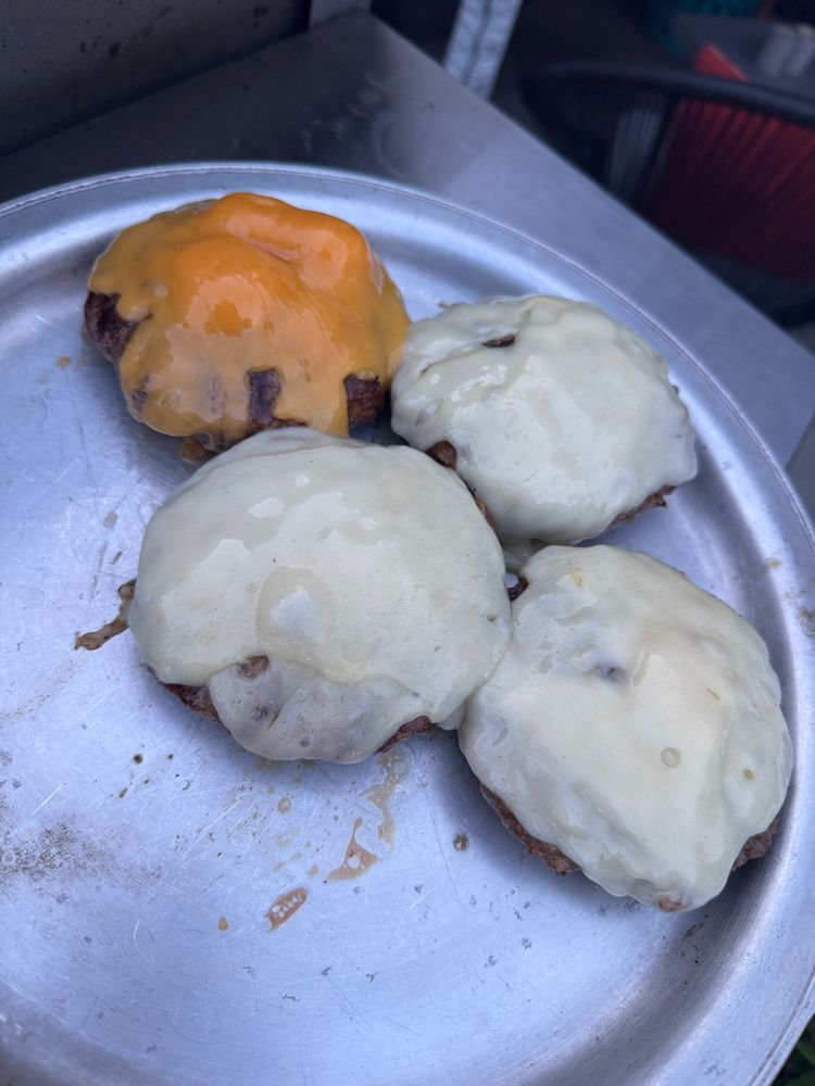 Four large burgers with cheese melted perfectly (3 Swiss 1 cheddar) on a silver platter.