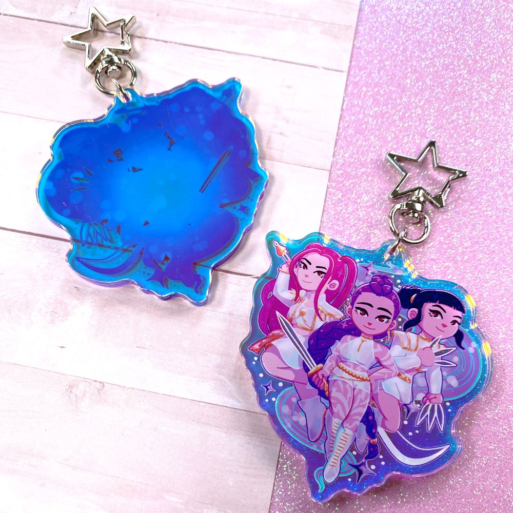 Another angle of the K-Pop Demon Hunters drawing and keychain, showing the backside which is a gradient color with more sparkles.