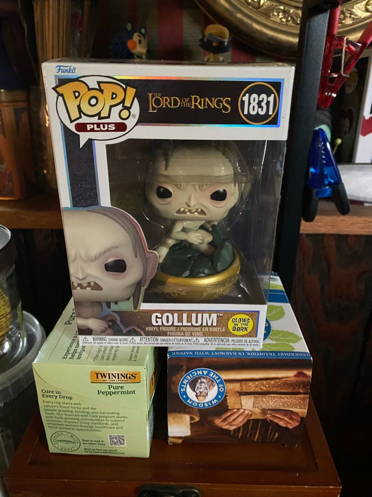 image: a pop funko figure of Gollum from The Lord of the Rings films/books. he’s grimacing in defensive anger atop a pile of rocks wrapped in the One Ring