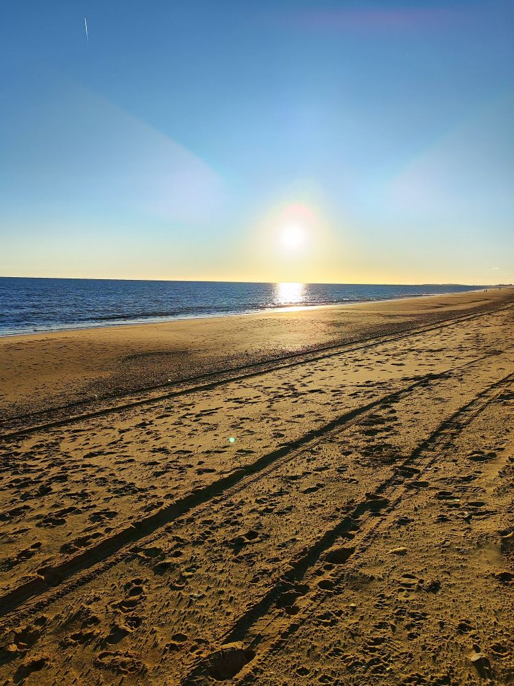 Imagen de una playa con el sol cayendo en el horizonte.