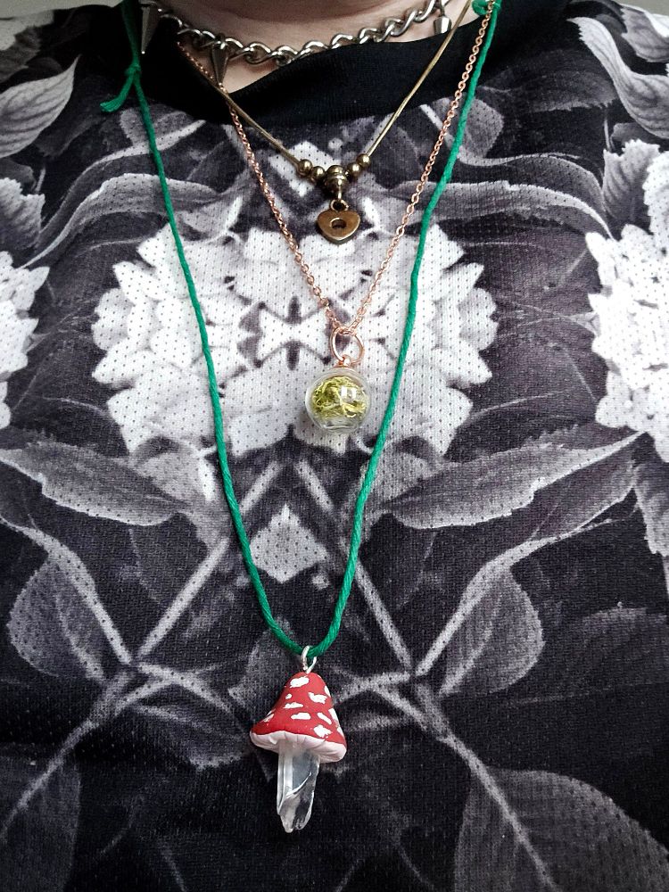 three necklaces: red and white mushroom with a crystal stem, small brass heart with a hole in the center, small clear ball with green moss inside (not gotten at the market but still worn)