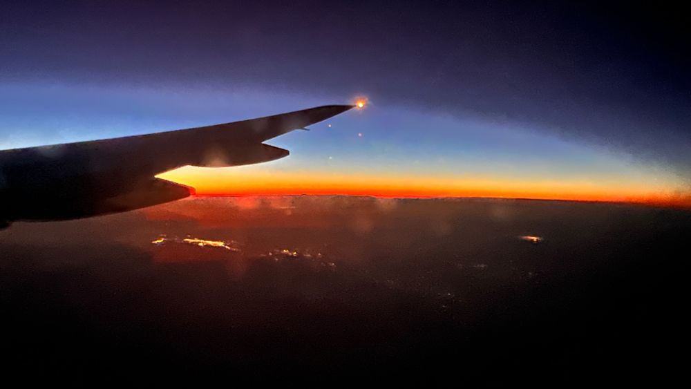Photo of a blue sky and sunset from plane window.