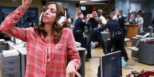 gina linetti from brooklyn 99 listening to music and enjoying herself while chaos happens in the background (so my mental state with america currently)