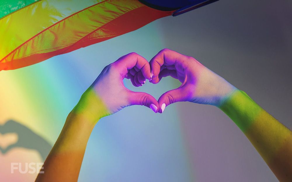 Hands with rainbows projected on them making a heart shape. Image from fusemagazine.com.au