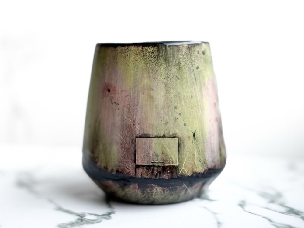 Angled cup resembling a weathered spacecraft with small rectangular hatch on the back (yellow green). 