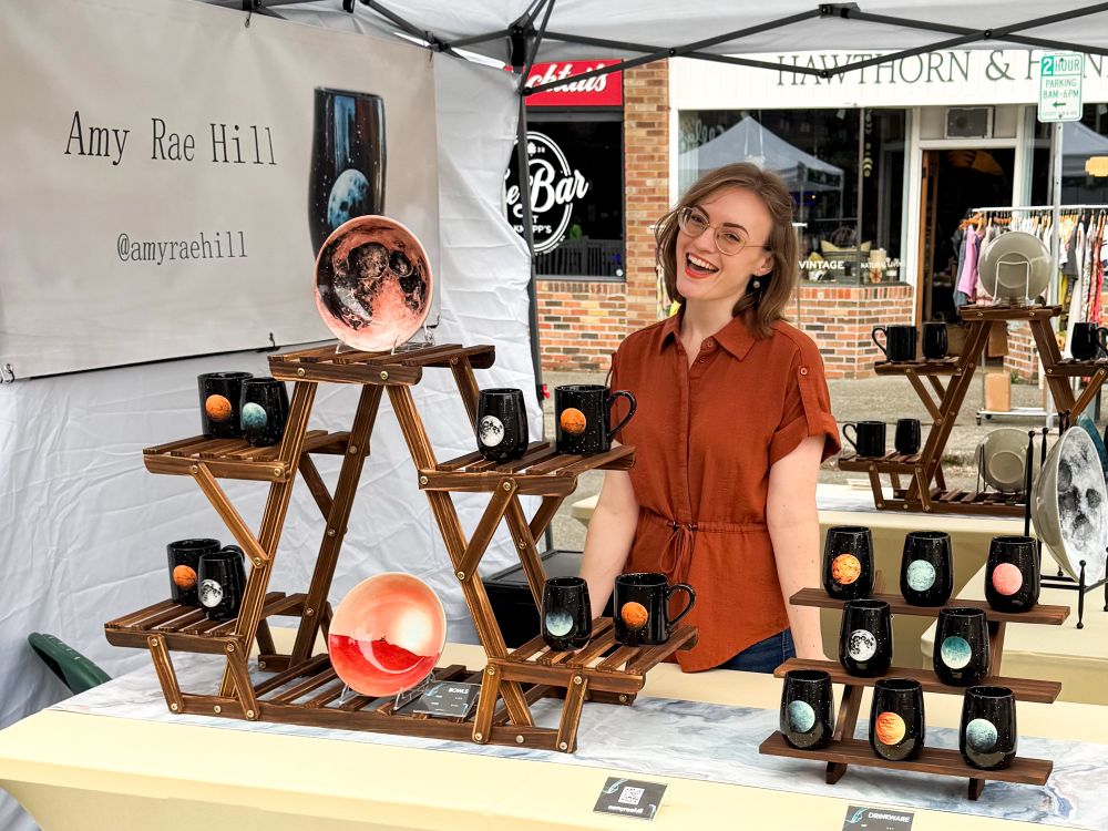 Me smiling behind a booth with a table of space pottery 