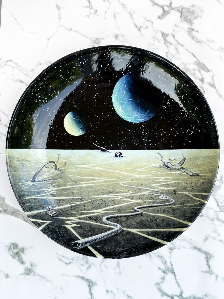 Serving bowl featuring two astronauts helping each off the ground in the distance near a crashed spaceship, while debris is scattered around the middle and foreground on the cracking surface of a barren moon. Two exoplanets above. 