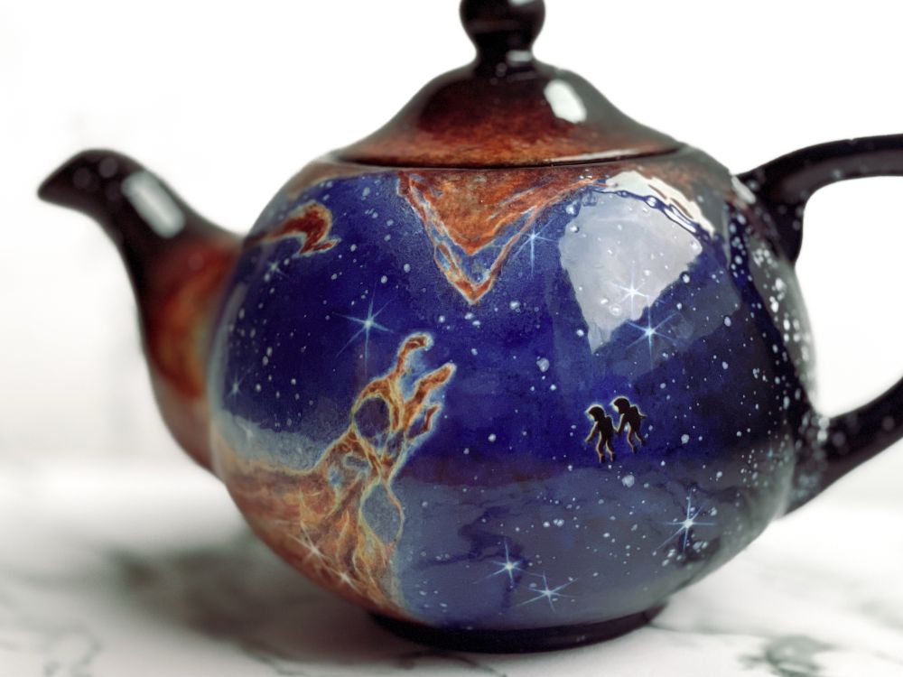 Teapot featuring the Eagle Nebula and two floating astronauts holding hands looking at the scene. 