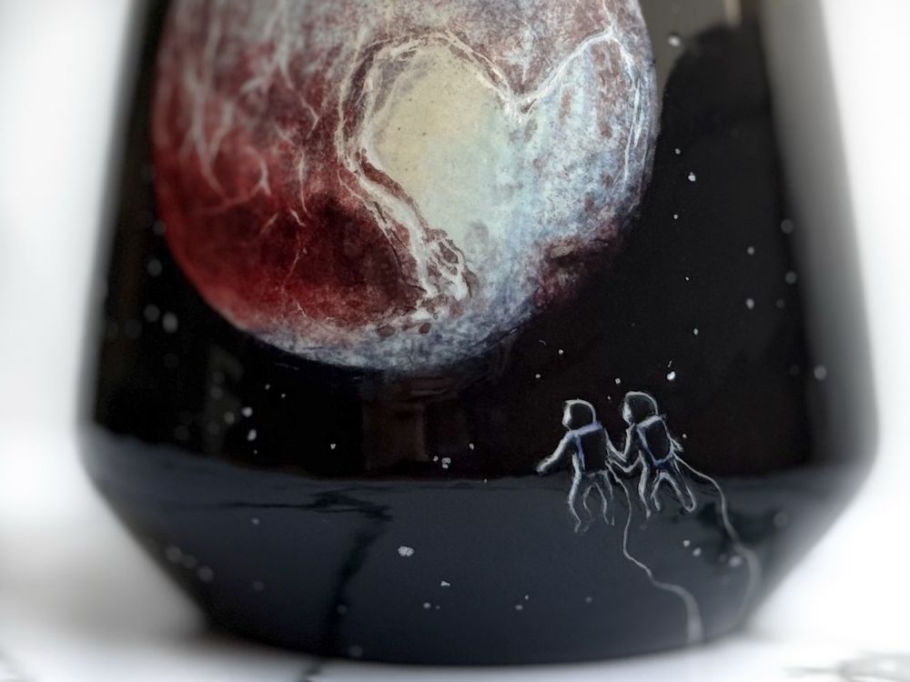 Detail of angled cup: two astronauts floating and holding hands looking at Pluto. 