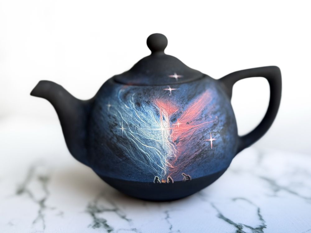 Teapot and mug featuring NGC 2313, teapot has a landscape with a couple people around a campfire and one looking through a telescope (detail of teapot)