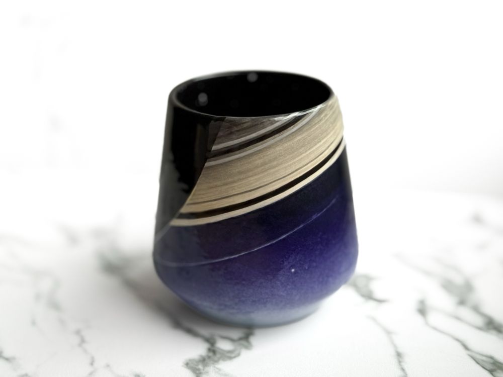 Angled cup featuring a hand painted design resembling the Cassini capture of Earth from Saturn as the "pale blue dot" (top)