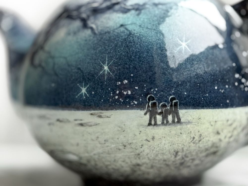 Detail of teapot: a family of three on a lunar landscape looking at the Milky Way and twinkling stars.