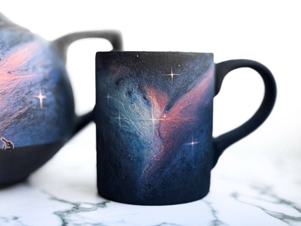 Teapot and mug featuring NGC 2313, teapot has a landscape with a couple people around a campfire and one looking through a telescope (detail of mug) 