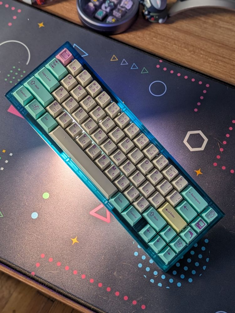 Translucent blue Photon mechanical keyboard backlit with a light visually floating on top of a deskmat
