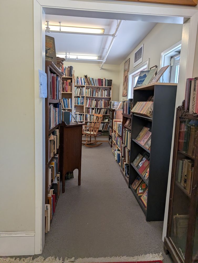 An antique bookstore showing a room with many bookcases filled to the brim with old books. In the background is a rocking chair.