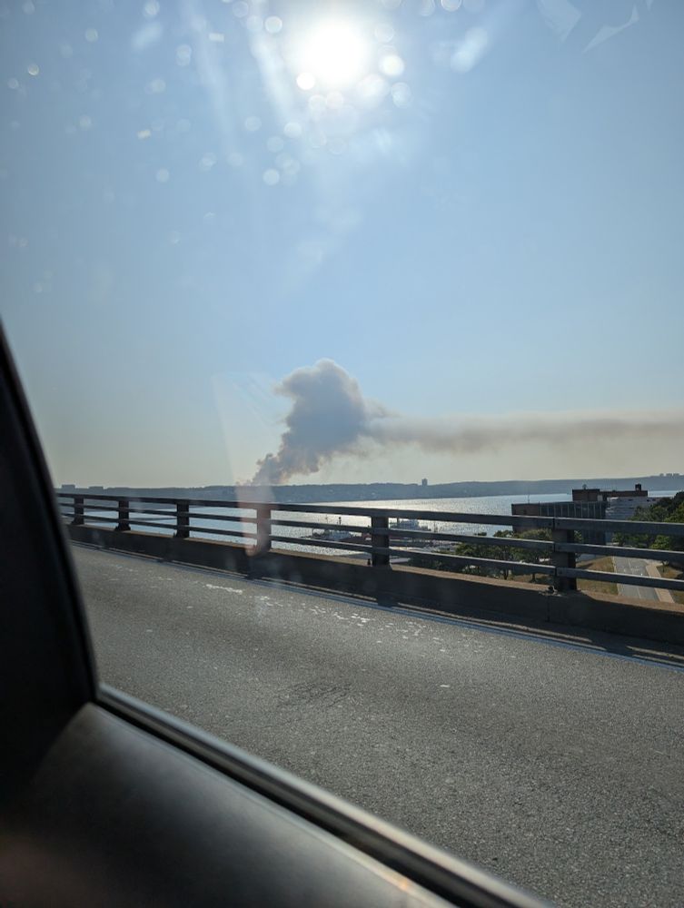 a photo from inside a car going across a bridge in Dartmouth. In the background is a large plume of smoke coming from a wildfire across the Bedford basin.