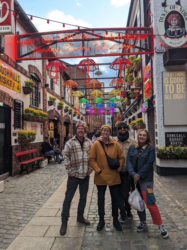 Nick, Healey, Alex and Lily standing and smiling at the entrance to Commercial Court in Belfast.