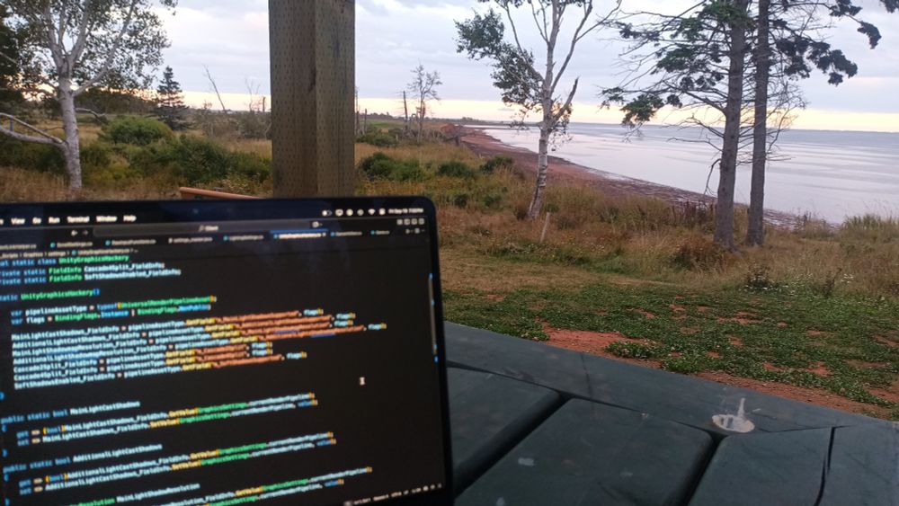Laptop computer open to some code, set up on a table next to the ocean