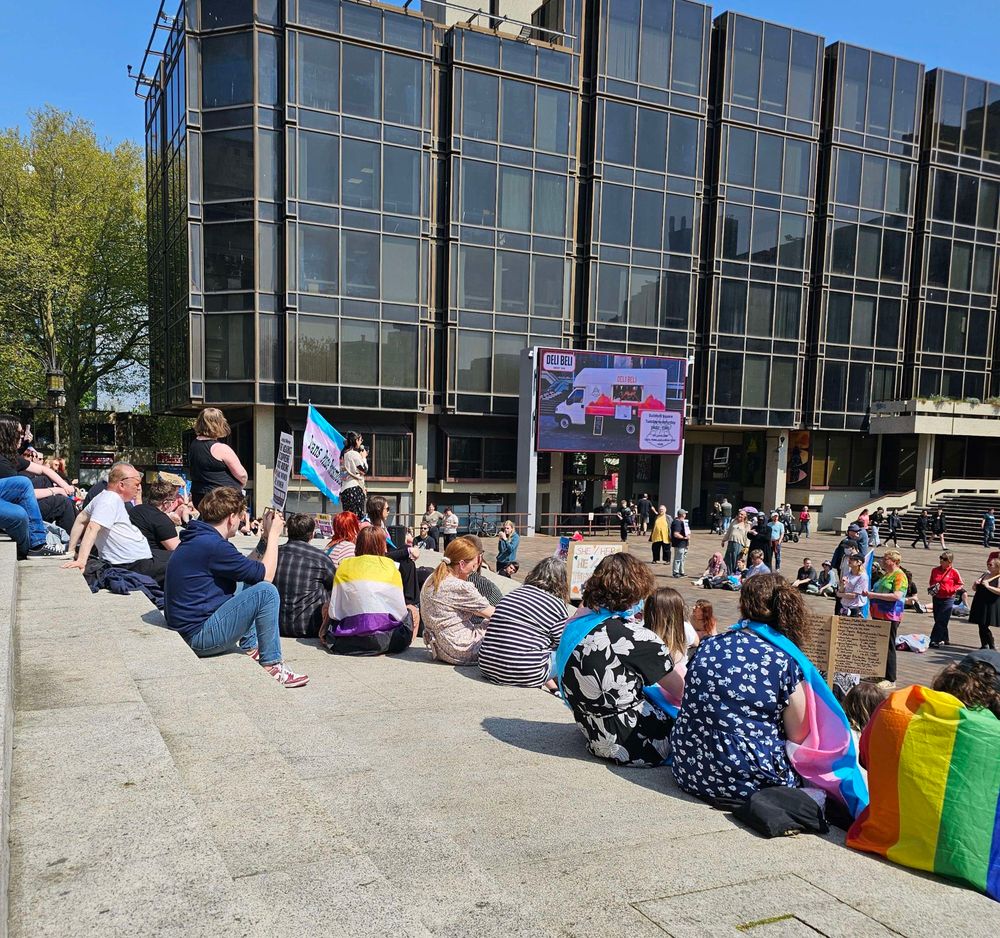Pic from the Trans Pride Portsmouth protest today. A very hot and sunny day with 200+ people sat on the steps of the guildhall and in the square. People are draped in queer flags, and listening to the final speaker of the day