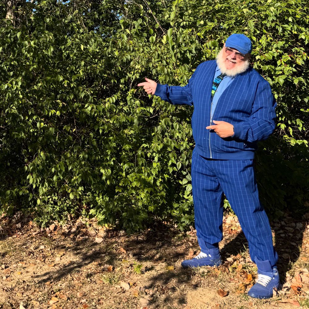 old guy in matching blue suit shown laughing and pointing at nothing 