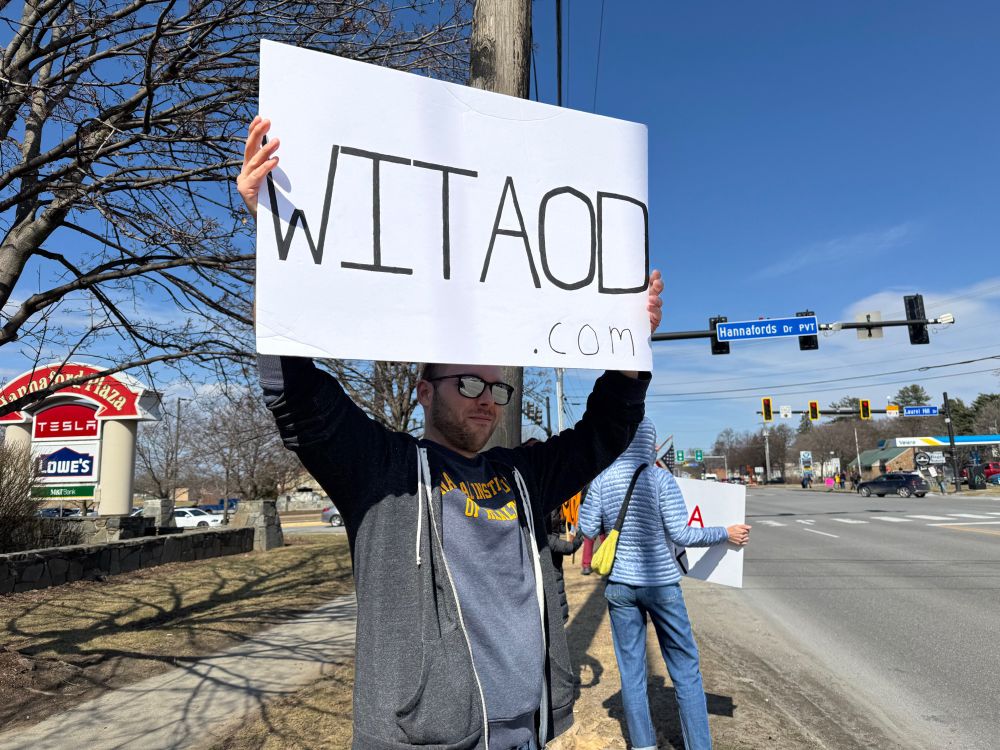 A man holding a WITAOD.COM sign in Vermont, February 2025