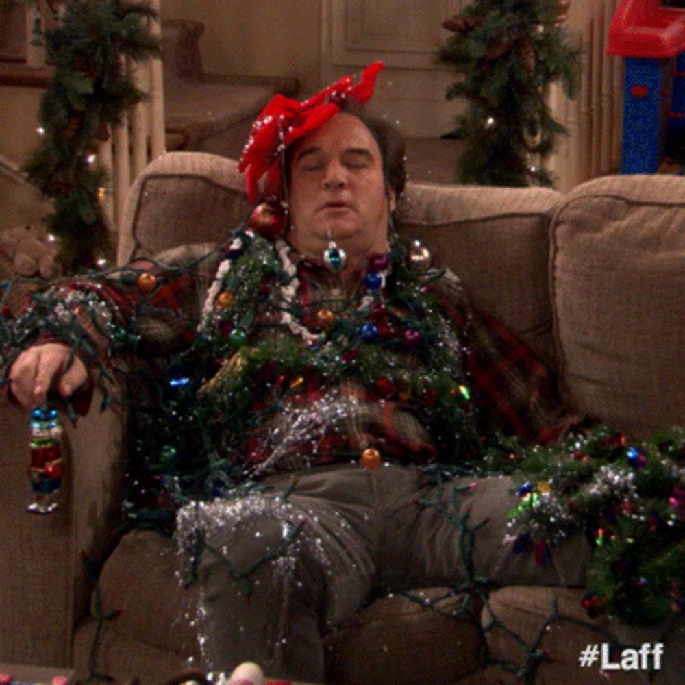 a man is laying on a couch with christmas lights around his neck