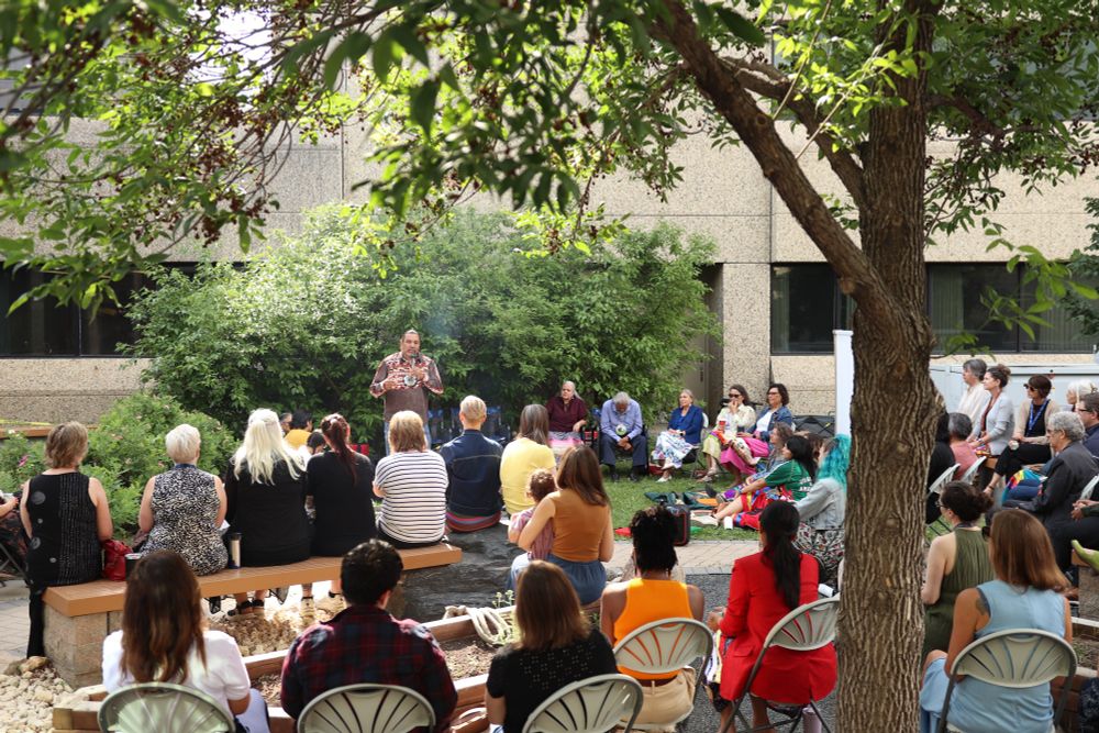 A group from the University of Manitoba gathers in the medicine garden to listen to knowledge keeper George Muswaggon.