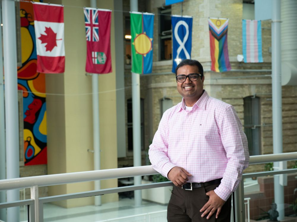 Student smiling at the camera with flags on the background.