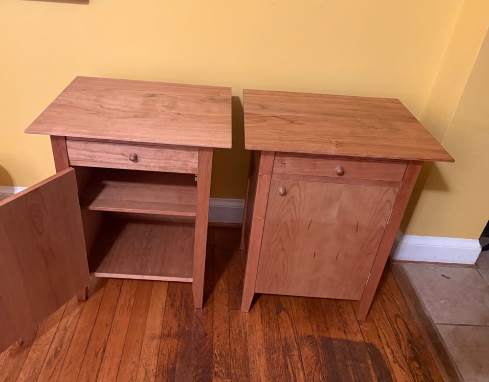 Two cherry nightstands- one has its door open