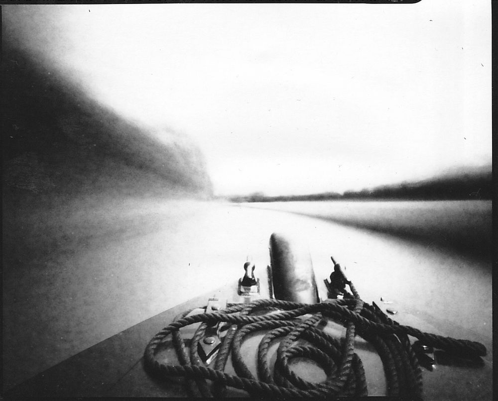 Black and white Pinhole photograph showing crisp in focus bow of canal boat against a smeary background 