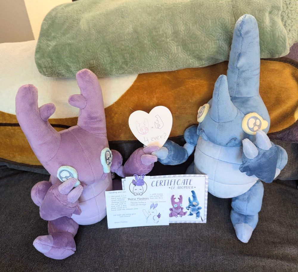 Two handmade beetle plushies holding hands