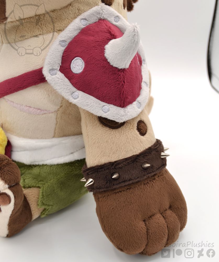 close up shot of our handmade gnoll plush, showing the arm, bracelet with spikes and shoulder plate