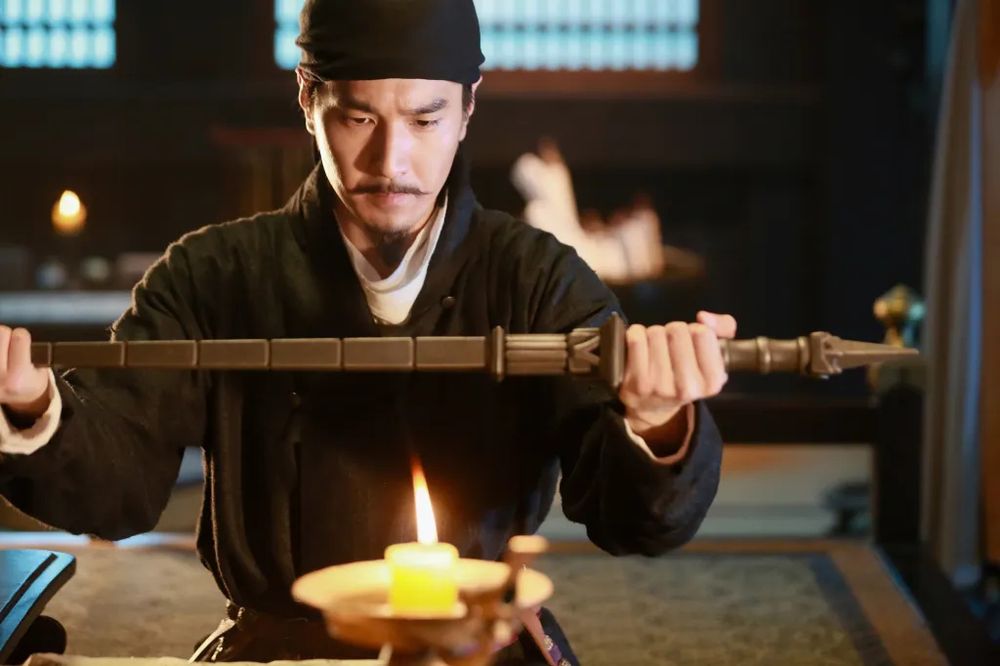 Detective Dee tenant cette épée carré au dessus d'une flamme