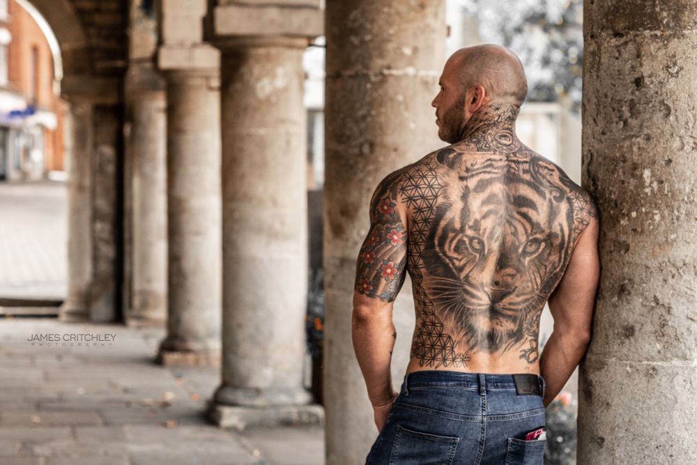 Hot male model Robin Hill pictured among ancient columns featuring his full back tiger tattoo.