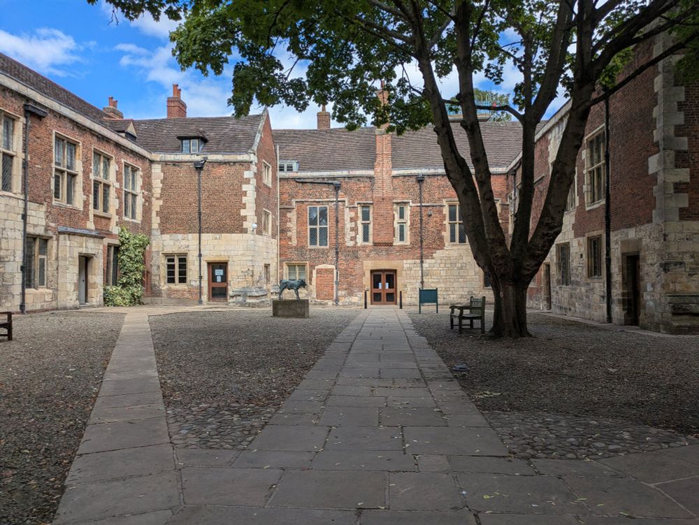 Kings Manor, York. A listed building courtesy yard featuring cobbled ground, benches, a statue and a tree.