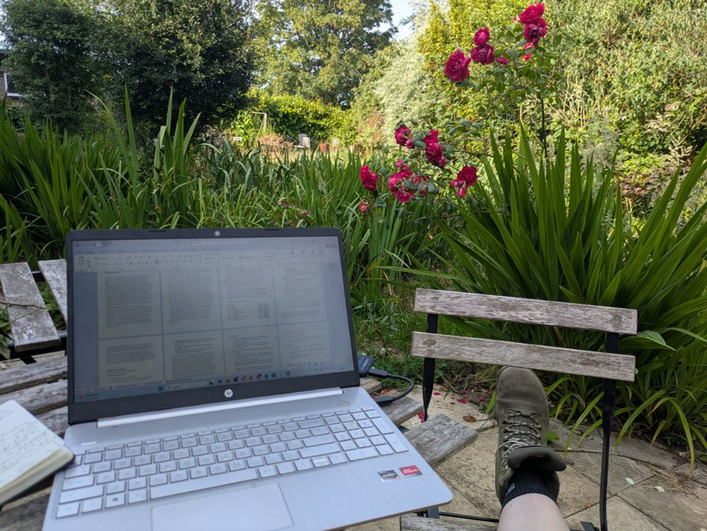 Laptop on a patio in an English garden with roses in the background 