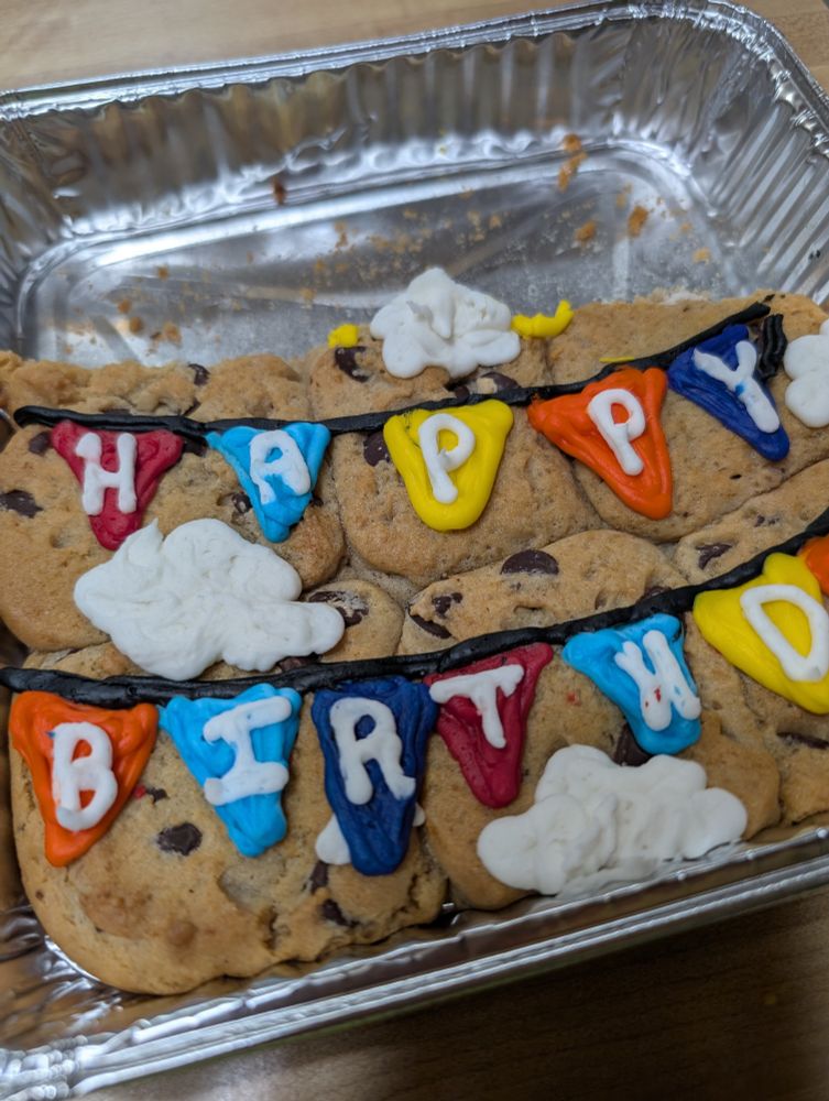 Partially eaten cookie cake that says "happy birthday" on it in icing.