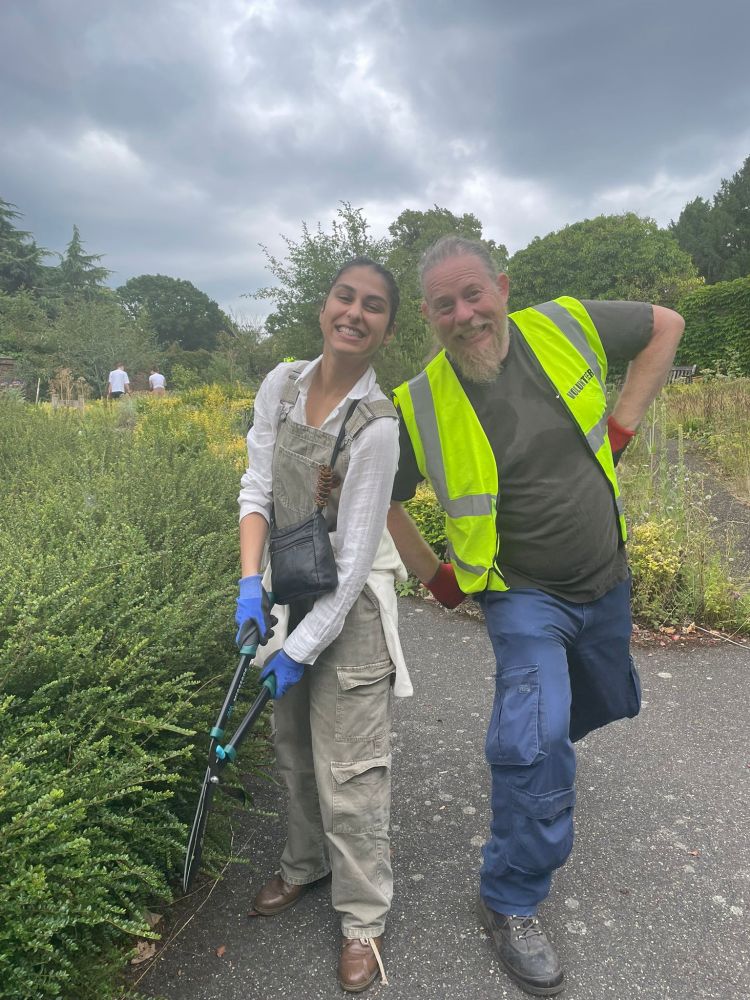 Peter and one of the volunteers smiling at the camera next to one of the hedges