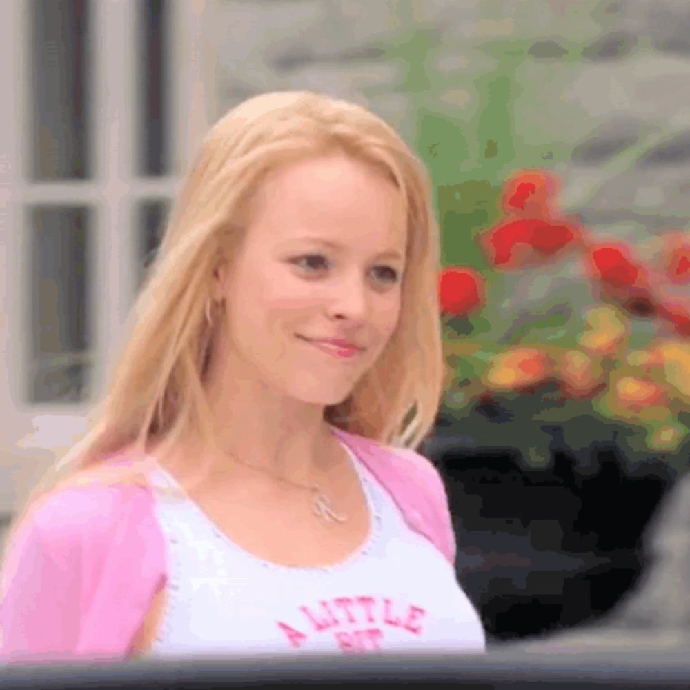 a woman wearing a white tank top that says a little bit on it