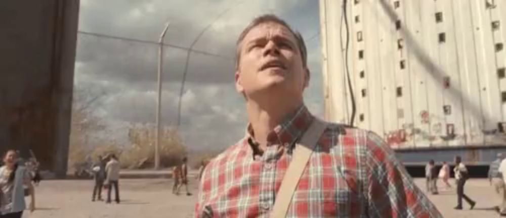 a man in a plaid shirt is standing in front of a building .