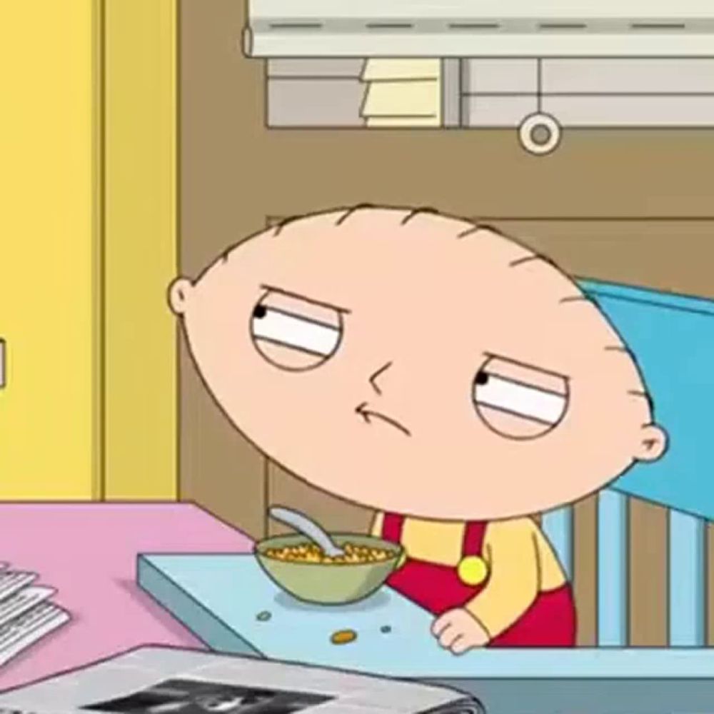 stewie from family guy is sitting at a table eating cereal .