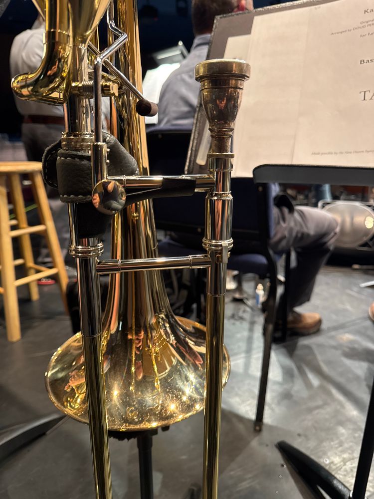 A bass trombone on a trombone stand at rehearsal. 