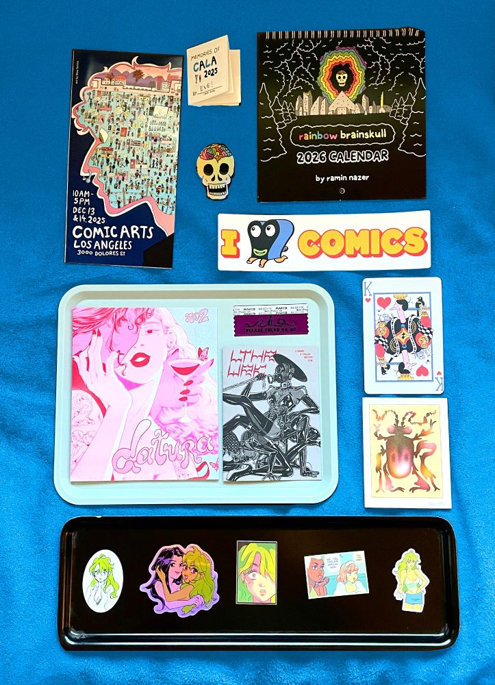 A bunch of zines and stickers and mini-prints laid out on a blue background 