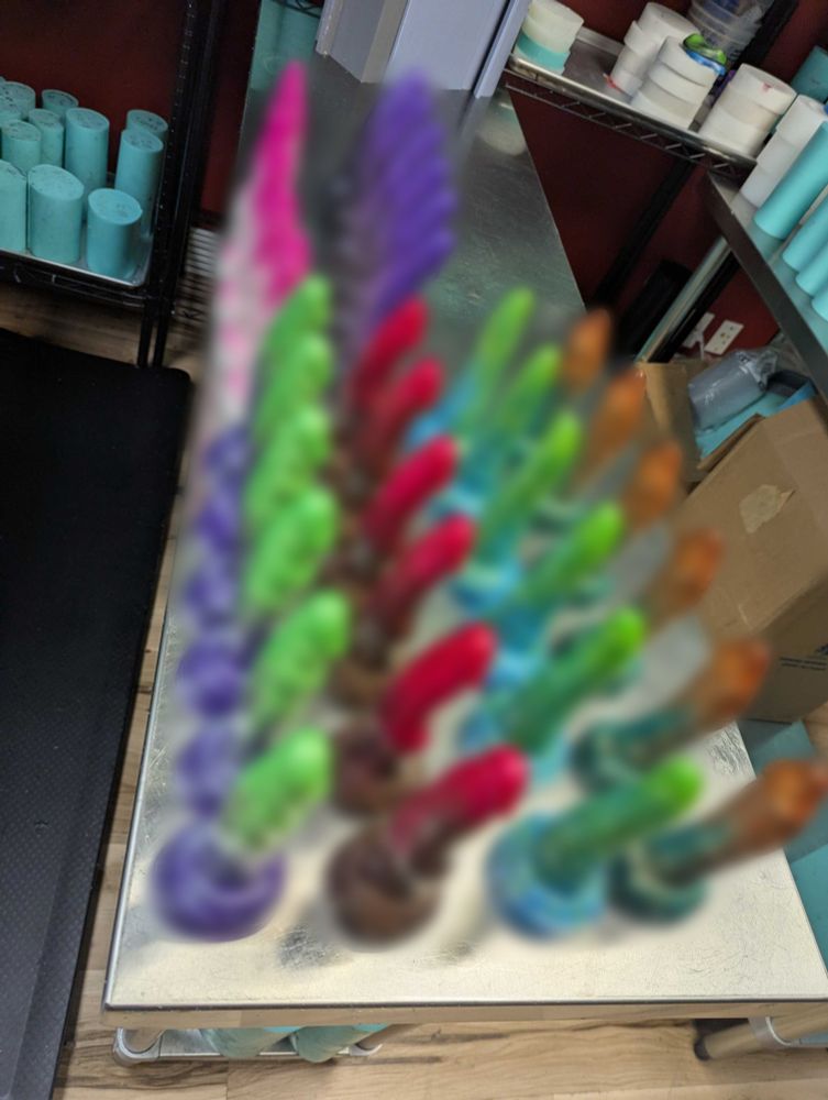 The same table, now lined with dildos. But the poster has applied a photoshop blur over the toys so only their vague silhouettes and colors are discernable. 