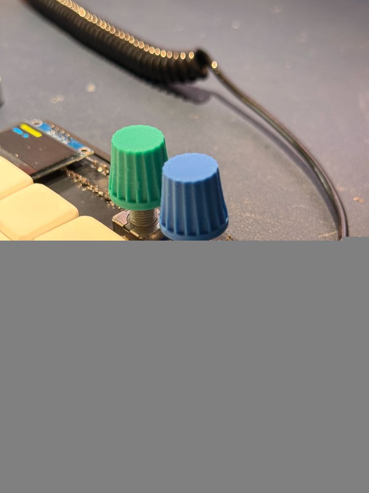 Foto mais próxima de uma das metades do teclado, mostrando além das teclas normais, quatro botões pequenos, dois encoders rotativos e o texto "Swan KB MK1".