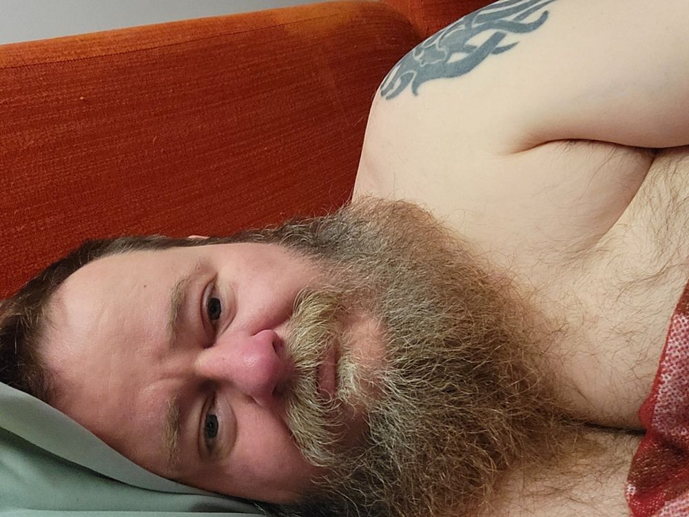 Bearded tattooed middle-aged man in bed.