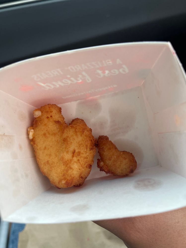 A really huge cheese curd next to a normal size one. 